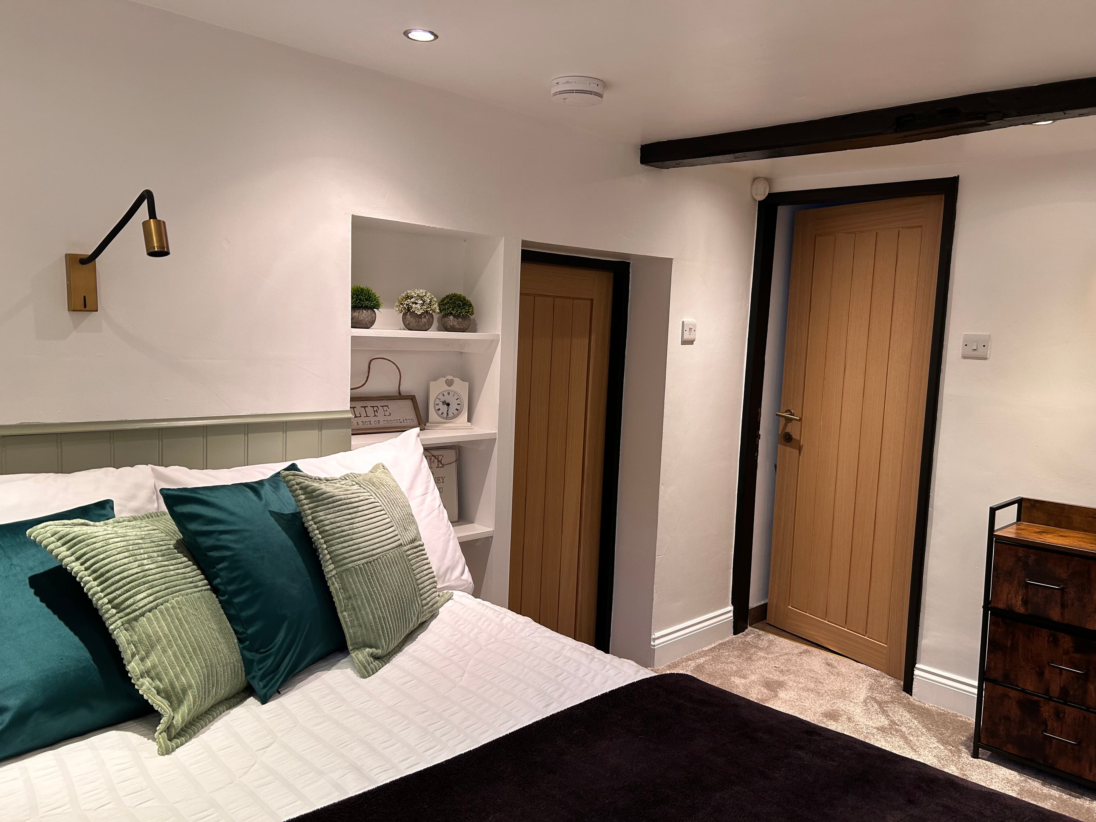 Cozy bedroom featuring a bed with green pillows, built-in shelving, and light wood doors.
